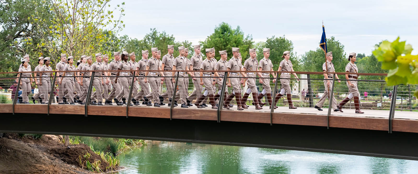 Photo of the cadets in formation crossing a bridge